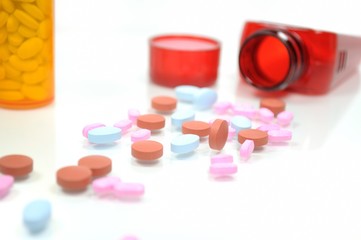 Red, pink and blue pills with traditional and red pill bottle.