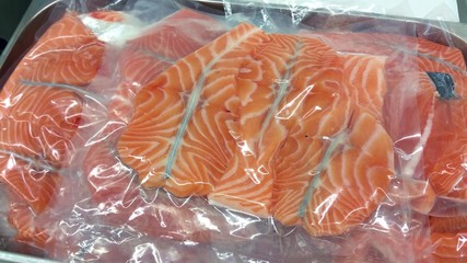 Lots of vacuum packed fresh salmon medallions, at a restaurant kitchen