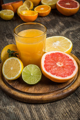 Citrus juice and fruits on vintage wooden background