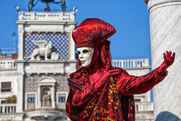 Fototapeta na wymiar Venetian Mask dressed in red Carnival costume posing in Saint Mark's Square Venice, Italy
