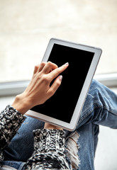 woman holding and using tablet with empty screen, ripped jeans