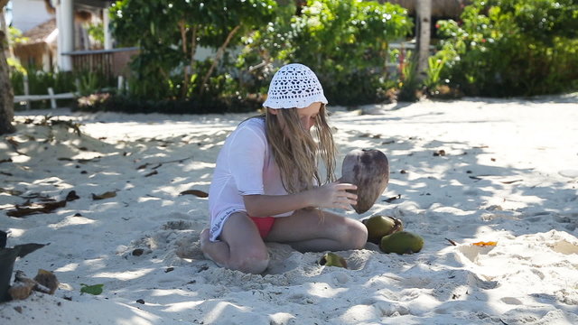 young girl playing with coconut on the beach.