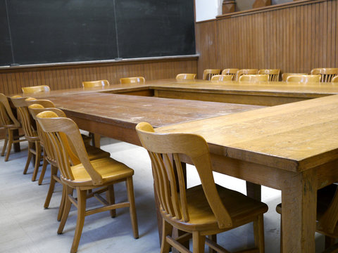 old fashioned wooden chairs and desks in classroom
