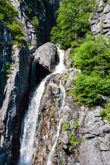 Mountain waterfall flowing down rocky cliff