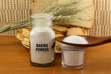 Obraz na płótnie Canvas baking powder in a glass jar and wooden spoon with cookie and bread