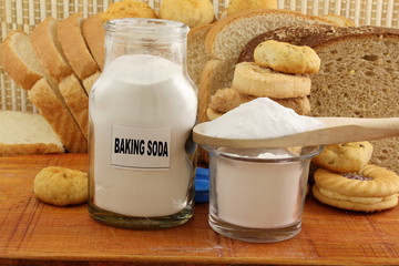 baking soda in a glass jar and wooden spoon with cookie and bread