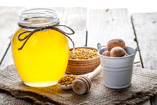 glass of fresh honey isolated and walnuts in a bucket