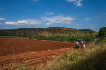 Red soil and manioc fields in Thailand with mountains in the bac