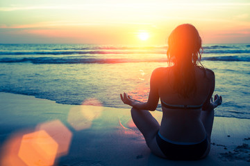 Yoga silhouette. Fitness and healthy lifestyle. Meditation girl on the background of the stunning sea and sunset.