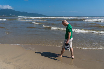 Young caucasian man walks on the beach of Da Nang, Vietnam.