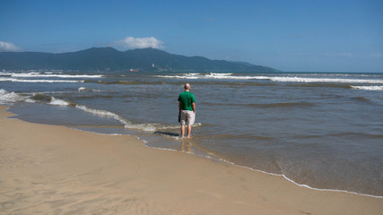Young caucasian stands on the beach of Da Nang, Vietnam.