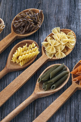 A set of raw pastas on spoons on a wooden table