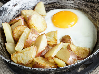 Fried potatoes with fried eggs, rustic breakfast, close-up