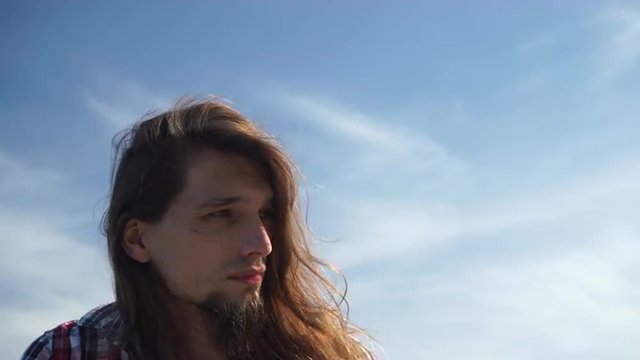 Man head long hair blowing on wind blue sky background 4K