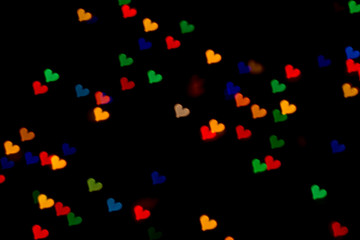 Fototapeta na wymiar beautiful bokeh made of warm blurred lights in the form of hearts on dark background