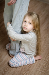 Young girl hugging her father's leg