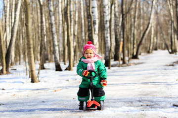 Fototapeta na wymiar little girl learning to ride scooter in winter