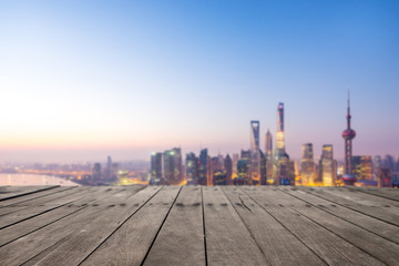 empty wooden floor and cityscape in blue sky at dawn