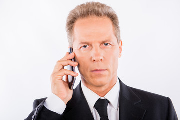 A serious mature businessman with modern mobile phone