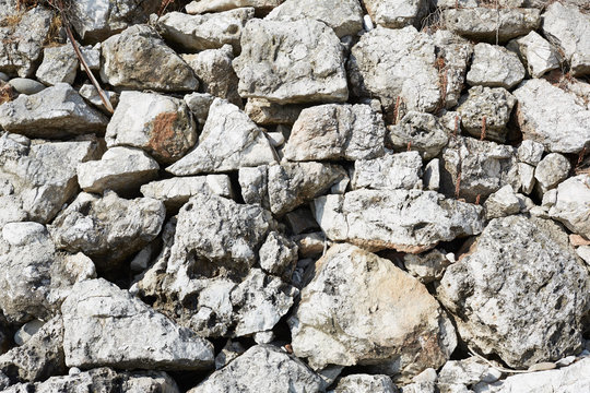 Rough stones dry wall texture background in sunlight, mediterranean coast