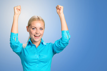 Pretty young blonde woman throwing her arms up into the air and laughing in jubilation at her success or victory