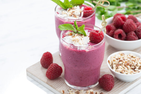 fresh berry smoothies with nuts on white board, closeup