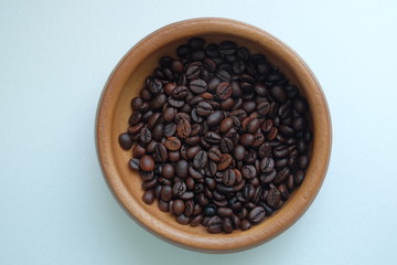 Roasted coffee beans in the wooden plate on a blue background