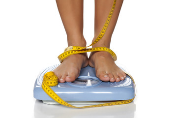 female feet on scale and measuring tape around them