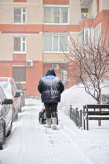 man removes snow in the yard of a multistory building with snow