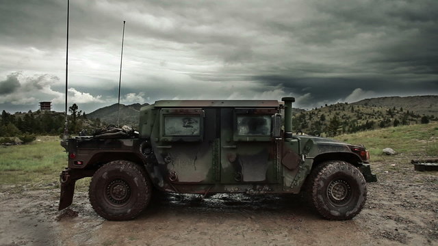 Humvee sitting in mud with storm clouds in the sky.