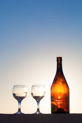 Glass and bottle with reflections of beautiful sunset. Selective
