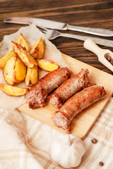 meat with vegetables , fried homemade sausage with roasted potatoes with garlic and pepper on a wooden background