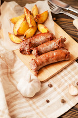 meat with vegetables , fried homemade sausage with roasted potatoes with garlic and pepper on a wooden background