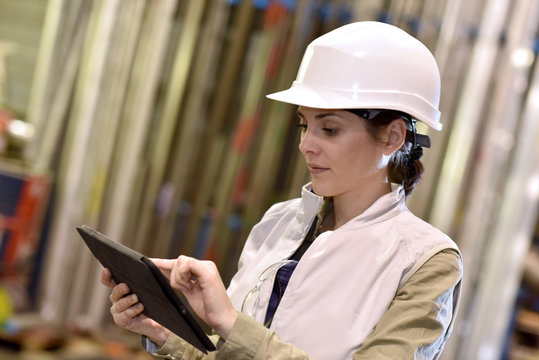 Woman in metal industry warehouse checking products