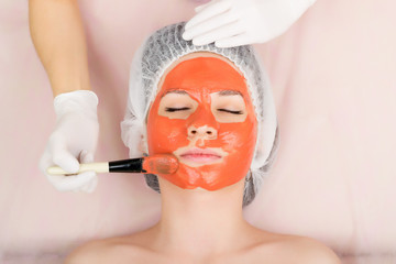 beautician does cosmetic mask on the patient's face, professional consultation. 