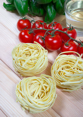 Raw homemade pasta and ingredients for pasta with tomatoes and basil.