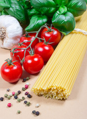 Raw pasta and ingredients for pasta with tomatoes and basil.