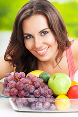 Woman with plate of fruits, outdoors