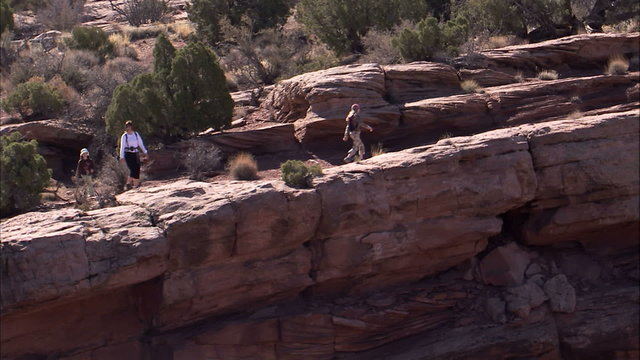 People hiking on a cliff.