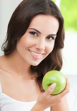 Young happy smiling woman with green apple, indoors