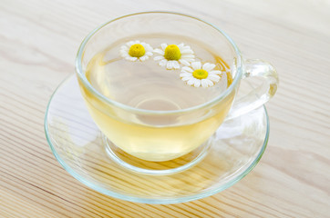 Obraz na płótnie Canvas Cup of medicinal chamomile tea on the wooden table