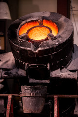 Steel worker in protective clothing raking furnace in an industr