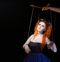 Red-haired girl stylized like marionette puppet on black background