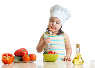 child girl in cook hat eating vegetables