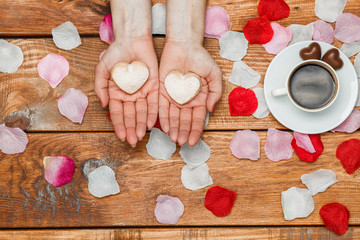 Valentines Day concept.  Female hands with  hearts on wooden background 