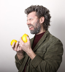 Mr. IceMan, smiling man with a beard, beard covered with hoarfrost, man holding lemon, he stares at them. fashion man in knitted sweater and jacket. 