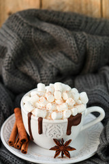White mug with hot chocolate, marshmallows and cinnamon on wooden table. Rustic style
