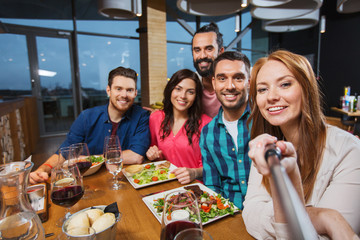 friends picturing by selfie stick at restaurant