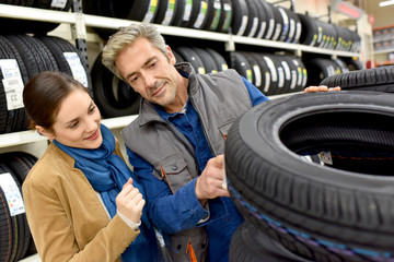 Customer in car shop choosing new tires with help of seller