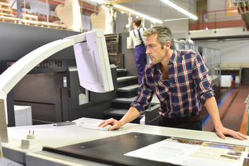 Man working on printing machine in print factory